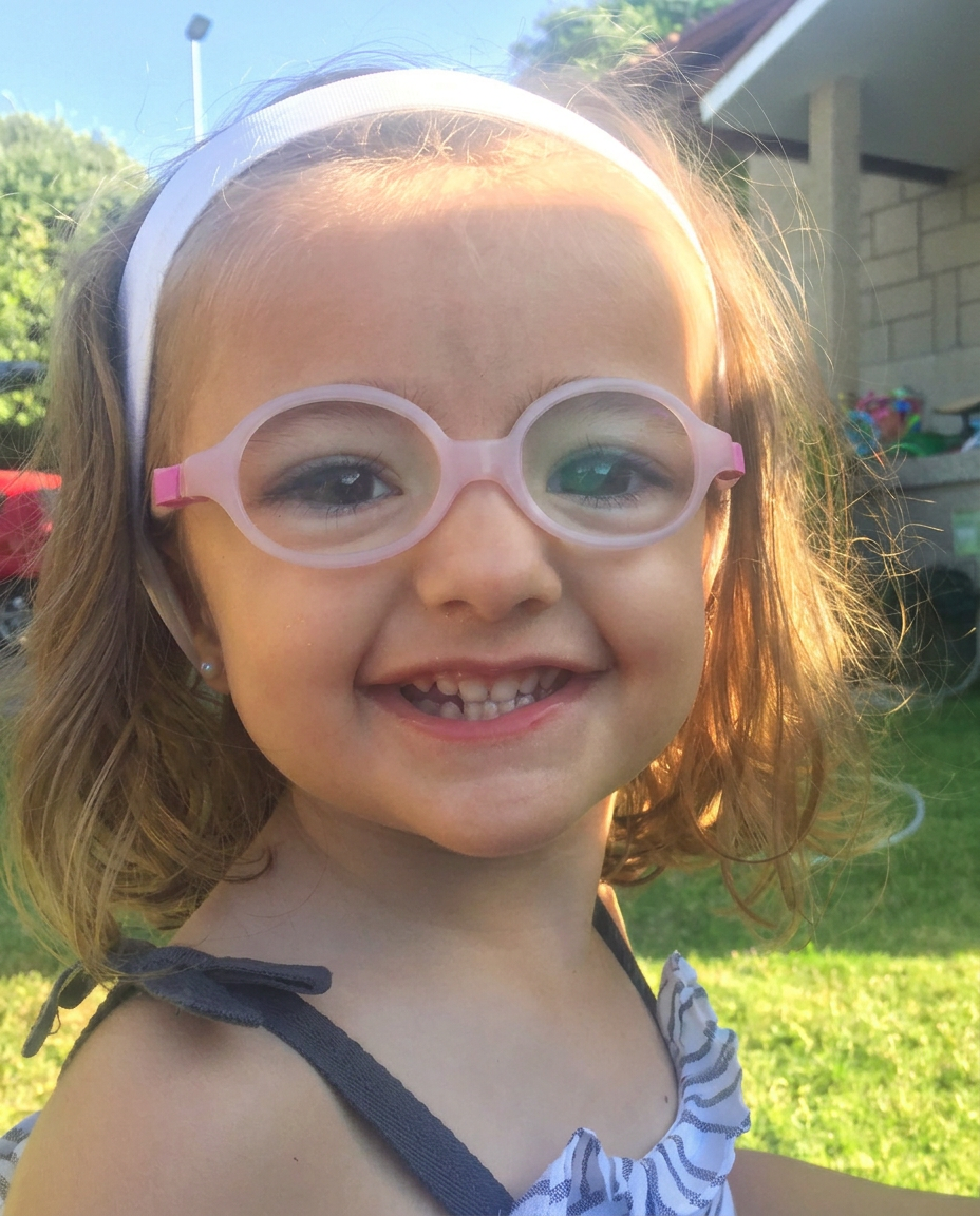 Iria sonriendo con gafas rosas en un jardín